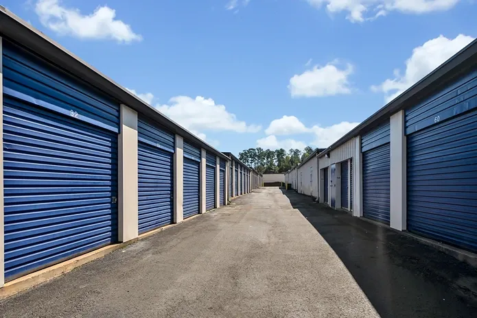 Wide drive aisle between rows of blue roll-up storage units for easy access